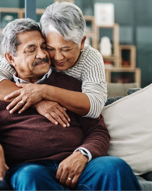 stock image of a man sitting on a couch with a woman hugging him from behind