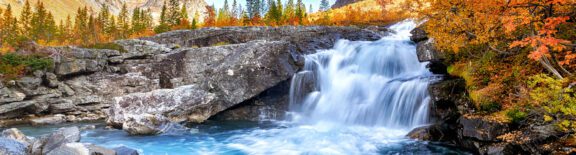 photo of a stone waterfall with colorful trees surrounding it