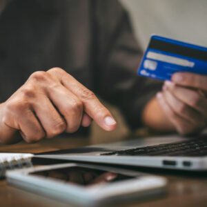 stock image of someone holding a credit card while typing the information on a computer