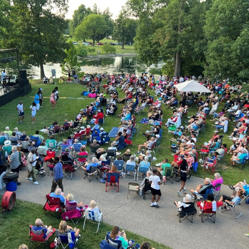 photo of a crowd seated on the lawn looking towards a stage at a concert at The Arlington Memorial Gardens