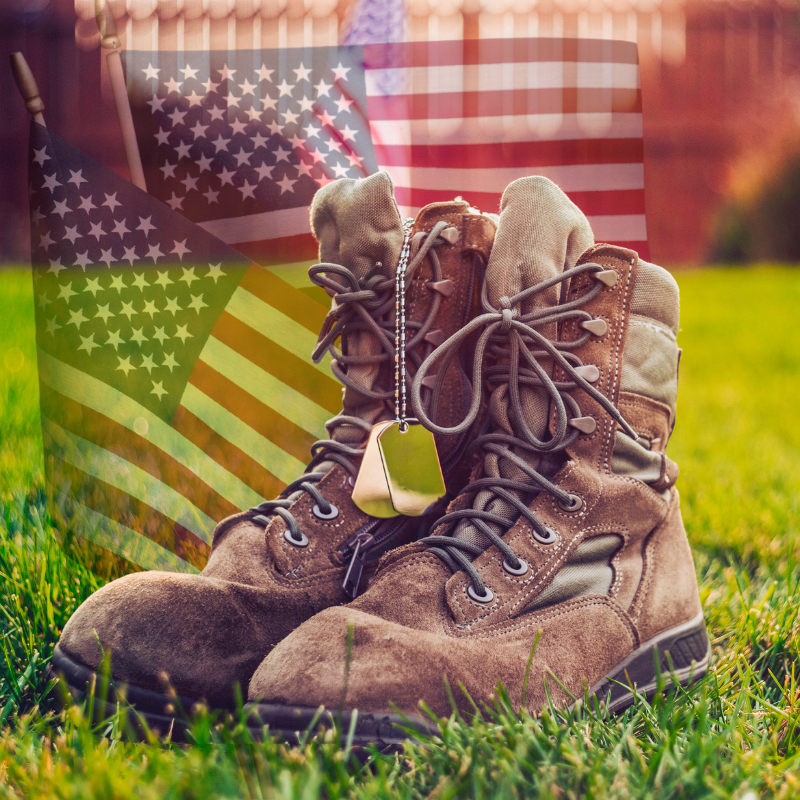 Celebrating Veterans Day Photo of brown combat boots with a dog tag hanging from the right boot and an American Flag faded into the image