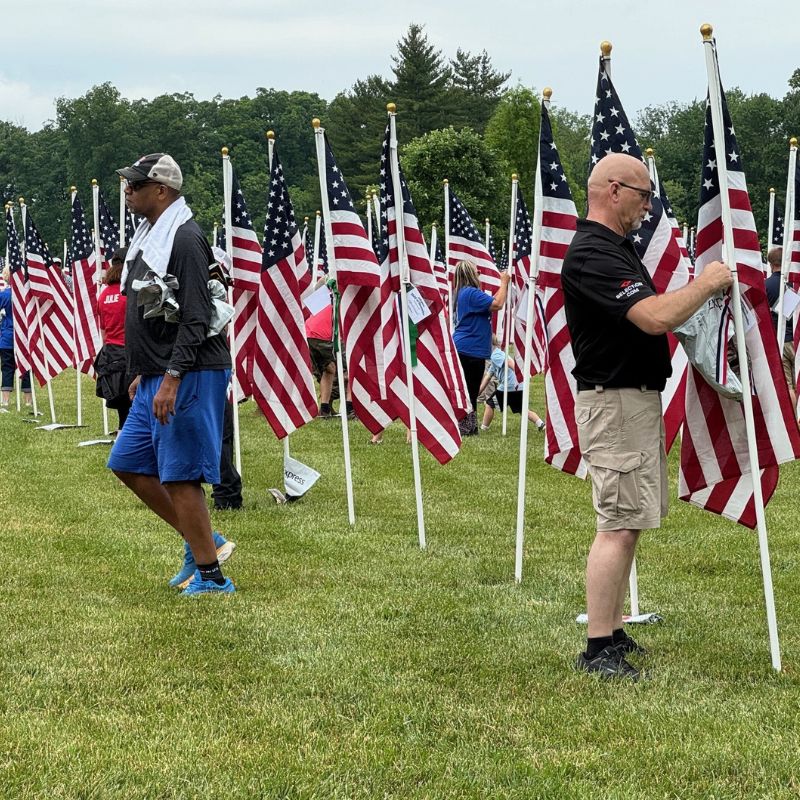 Volunteers placing American flags in the ground for Memorial Day