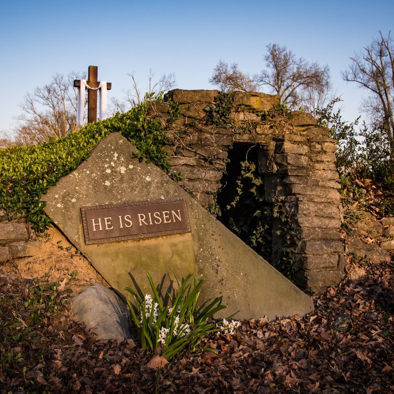 Photo of an empty tomb with words inscripted on the tomb door that say "He Is Risen"