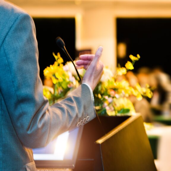 Funeral Celebrant at Podium with yellow flower bouquet in front of attendants