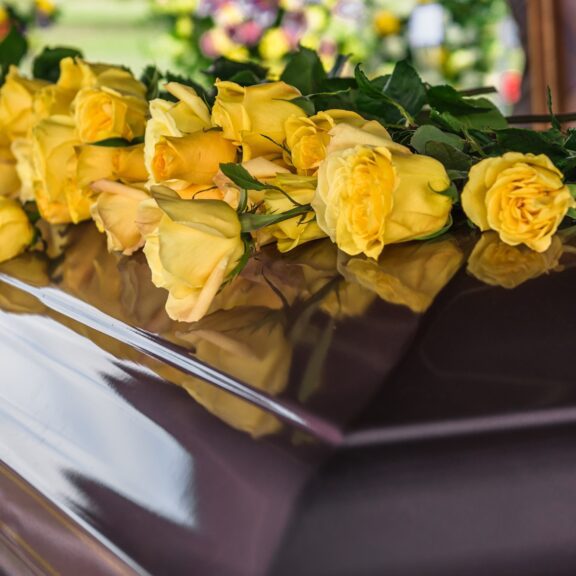 Yellow Rose Flowers on Casket at Funeral Service in a Cemetery